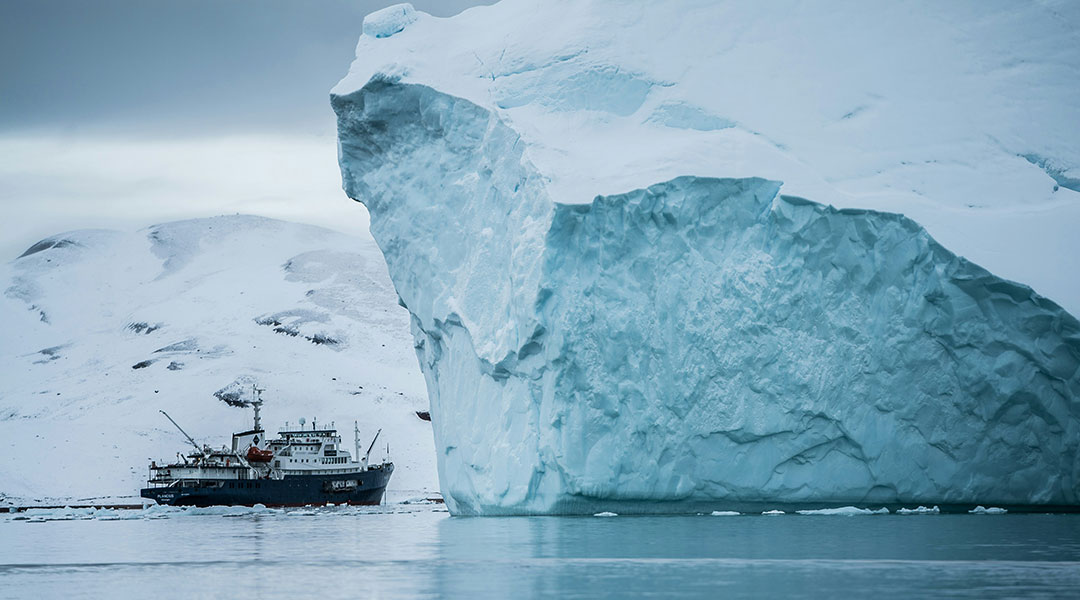 A ship sailing past an iceberg in Greenland.