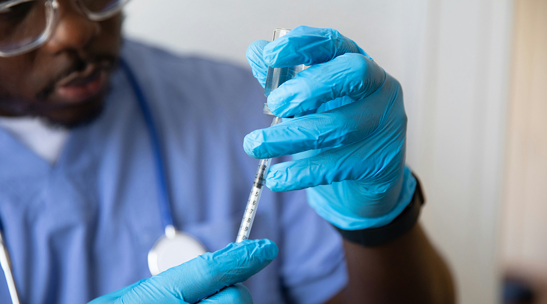 A scientist withdrawing liquid into a syringe.