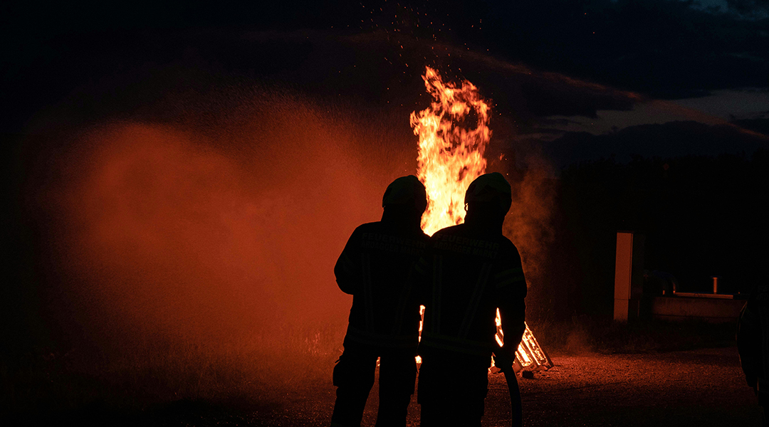 Fire fighters against a smokey backdrop.