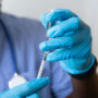 A scientist withdrawing liquid into a syringe.